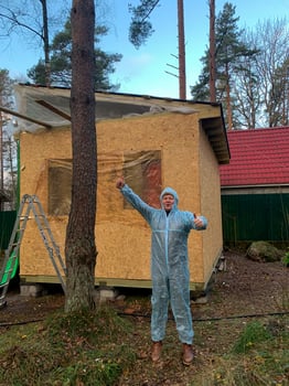 A jubilant man in a protective suit celebrates construction completion amidst rustic woodland, nodding to DIY Earth Day projects photo
