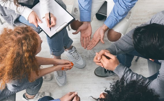 Trust circle. Diverse people sharing their problems with psychologist at group therapy session, counselor taking notes to clipboard, top view photo