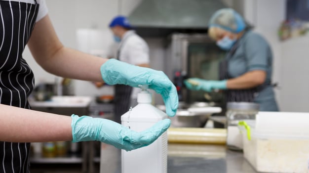 Take away kitchen workers disinfecting hands with spray detergent, panorama, blurred background photo