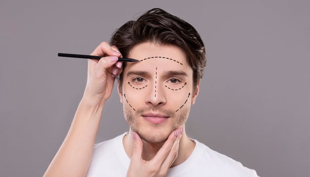 Face lifting. Doctor touching male face with correction lines for cosmetic surgery, drawing marks, gray background photo