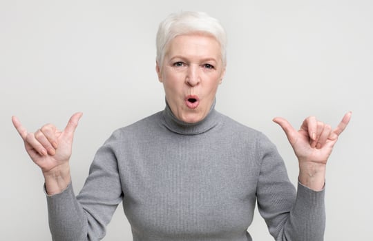 Cool grandmother showing modern trendy rock gesture on light studio background, copy space photo