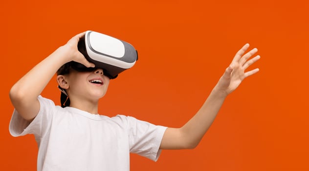 Innovation in real life. Emotional teenager enjoying virtual reality on orange background, empty space photo