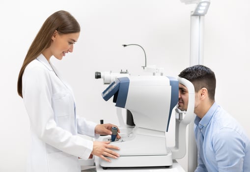 Medical Center. Female ophthalmologist checking eye vision of handsome young man in modern clinic, side view photo