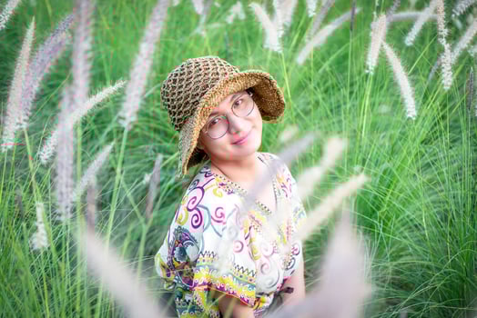 A girl in a hat and glasses in a field of tall grass photo
