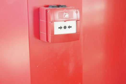 Fire alarm box mounted on a bright red wall indoors photo