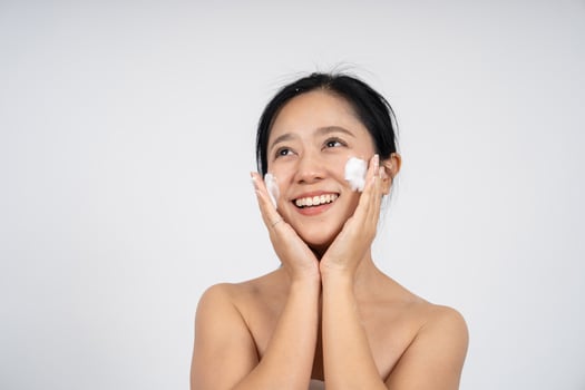 Skin care concept. Cute Asian woman is washing face on white background photo