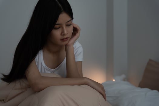asian woman in bed late trying to sleep suffering insomnia, sleepless or scared in a nightmare, looking sad worried and stressed. Tired and headache or migraine waking up in the middle of the night photo