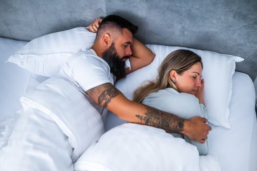 Young married couple embraces lovingly while sleeping peacefully in their cozy bedroom. Their relaxed posture reflects comfort and intimacy in a real life moment. photo