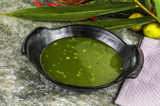 A bowl of green soup with a spoon and a knife photo