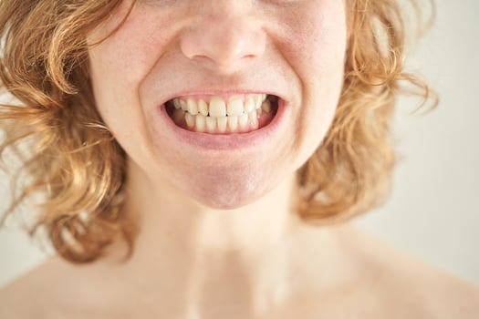 Close-up of young caucasian female smiling with curly hair and visible teeth. photo