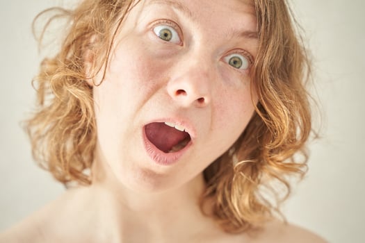 Caucasian female with curly hair showing surprised expression close-up portrait. photo