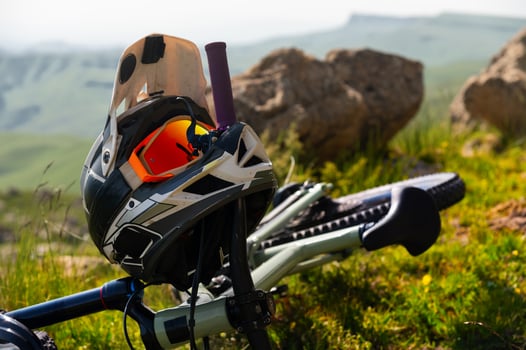 Close-up Mountain bike with helmet and mask lying on grass high in mountains against mountain landscape of rocky mountains and valleys. Nobody photo