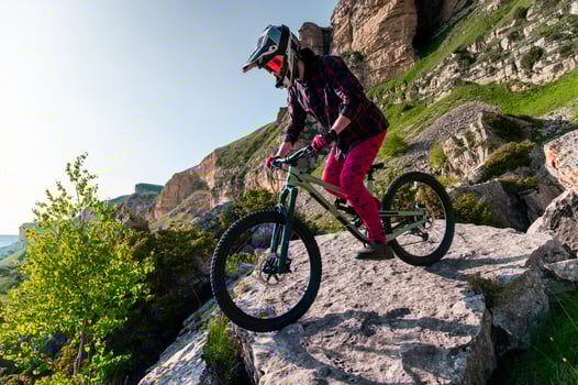 Cyclist in red riding a bike on a rocky trail off-road. Extreme sports and enduro bike concept photo