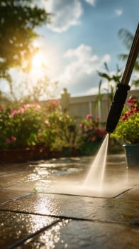 Woman pressure washing backyard patio, water spraying off dirt from stone tiles. photo