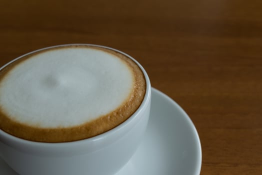 A cappuccino is sitting on a saucer photo