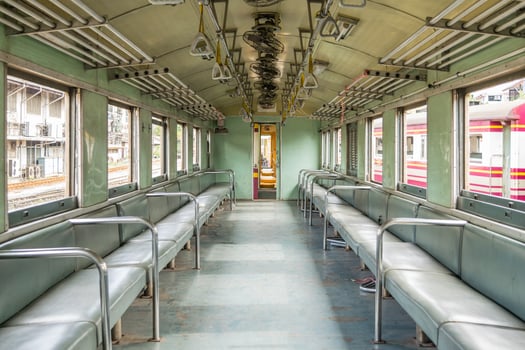 A train car with empty seats and a metal railing photo