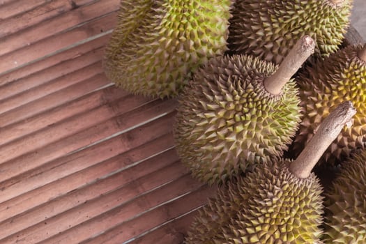 A bunch of durian fruit sitting on a wooden table photo