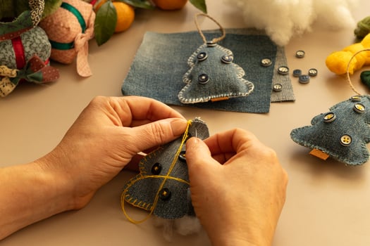 Female hands sews a felt Christmas tree on a light background. Christmas tree made from old denim. photo