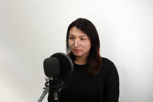 A woman wearing glasses and a black shirt is recording photo