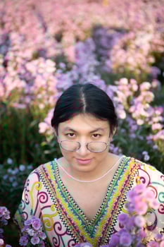 A woman wearing glasses in a field of flowers photo