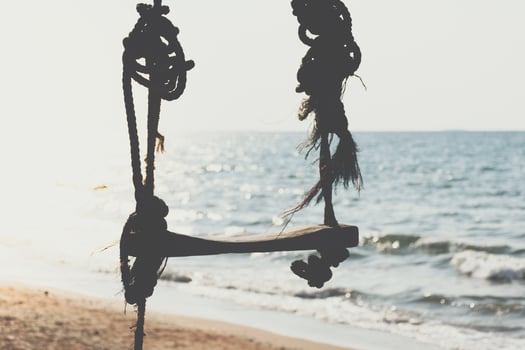 A swing hanging from a rope on the beach photo