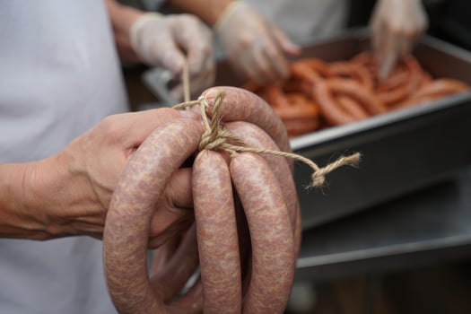 Hands tying rope around sausage links during the food preparation process in a kitchen. photo