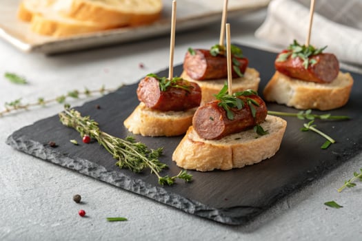 Grilled sausage slices served on toasted bread with fresh parsley, a perfect appetizer. photo