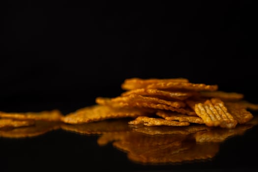 Golden ridged potato chips piled on a dark reflective surface, emphasizing their crispy texture and delicious snack appeal for a quick bite photo