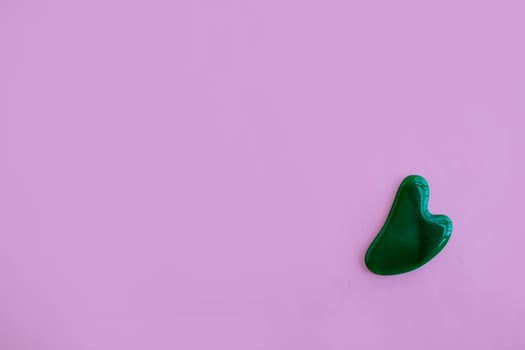 Jade massager on a pink background. Background with copy space. photo