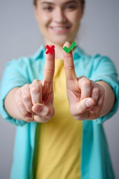 Young Woman Holding Red Cross and Green Check Marks on Fingers photo