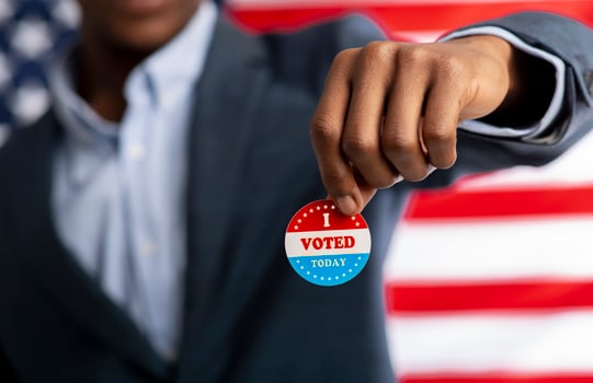 Unrecognizable african citizen of America holds I voted today button, typical of US elections on American flag. photo