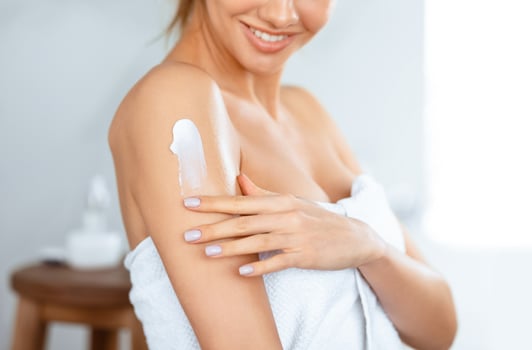 Body Care. Woman Applying Moisturizing Lotion Or Cream On Shoulders Caring For Skin At Home, Standing In Bathroom. Skincare And Pampering, Beauty Routine Concept. Cropped, Selective Focus photo