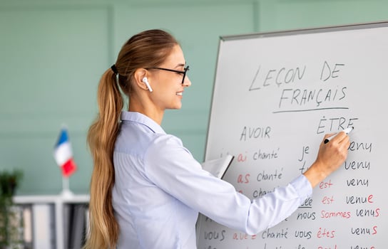 Remote education and tutoring concept. Female teacher writing grammar rules on whiteboard during online French lesson, happy tutor teaching foreign language on web photo