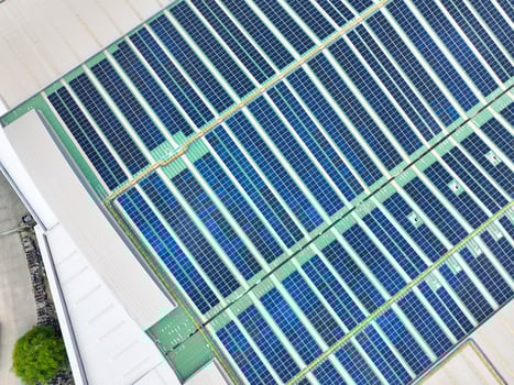 Solar panels on industrial factory rooftop. Renewable energy. Sustainable manufacturing. Green technology. Rooftop solar power. Commercial buildings with efficient renewable energy infrastructure. photo