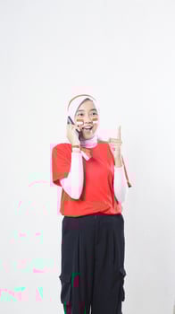 Indonesia independence day celebration concept with happy Asian girl wearing red and white Indonesia flag color attribute talking on the phone call isolated on white background photo