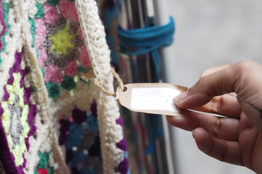 Hand reaching for a tag on a colorful crochet blanket photo