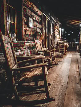 Rustic Wooden Rocking Chairs on a Log Cabin Porch at Night. A close up view of antique wooden rocking chairs on a wooden porch. photo