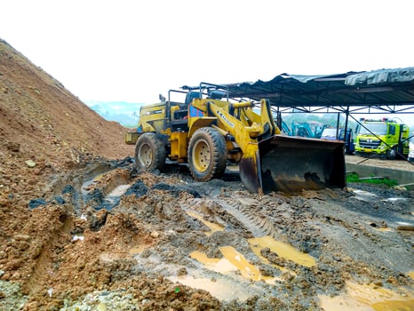 A yellow bulldozer is parked in a muddy field photo