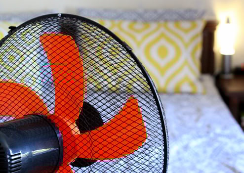 Cooling down the air temperature in the bedroom during hot and stuffy summer with the power of an electric home floor fan. photo