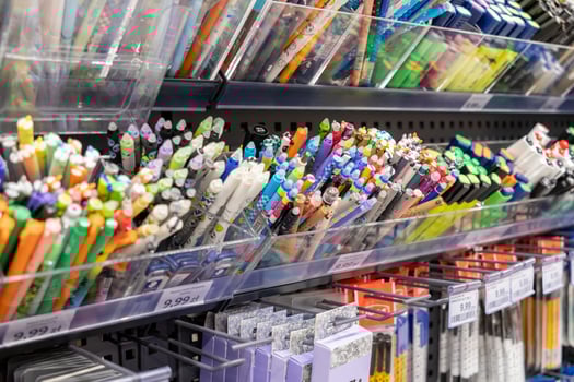Numerous colorful pens and pencils neatly arranged on display shelves in a retail store, offering a wide selection for school supplies or office use photo