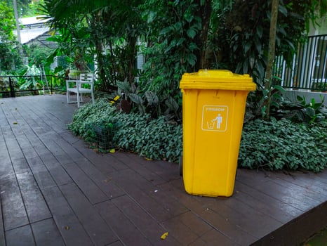 A yellow trash can sitting on a wooden deck photo