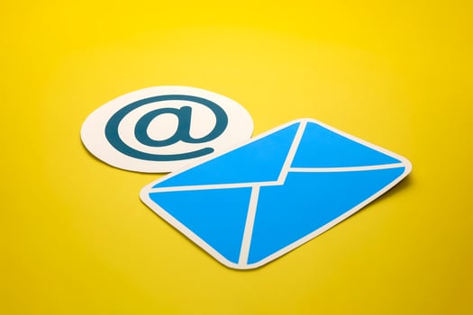 Paper letter and at sign on yellow background, with copy space. Business concepts of online contact channels, and electronic mail inbox notifications. photo