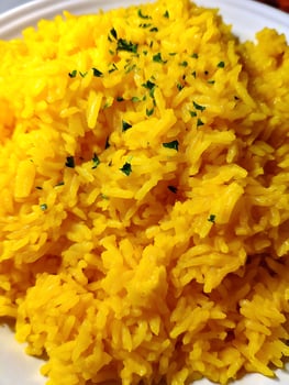 Close up of a serving of vibrant yellow rice, garnished with fresh herbs. photo