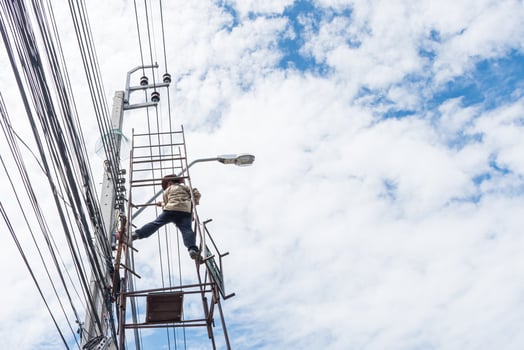 A man on a ladder on top of an electric pole photo