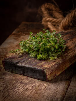 Fresh Thyme Sprigs on Rustic Wooden Board. A close up image of vibrant green thyme on aged wood, perfect for culinary or herbal themes. photo