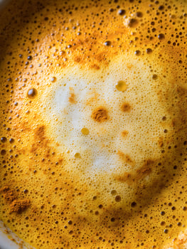 Close up of Golden Turmeric Latte Foam Texture. A detailed image showcasing the rich, bubbly texture of a turmeric latte. photo