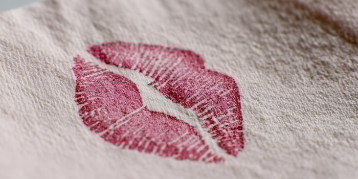 Lipstick kiss mark on a white cotton face mask on pastel pink background photo