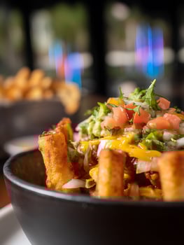 Close up of Chili Cheese Fries with Guacamole and Pico de Gallo in a Black Bowl. photo