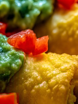 Close Up of Fried Food Topped with Guacamole and Tomatoes. A Detailed Image of Delicious Mexican Cuisine. photo