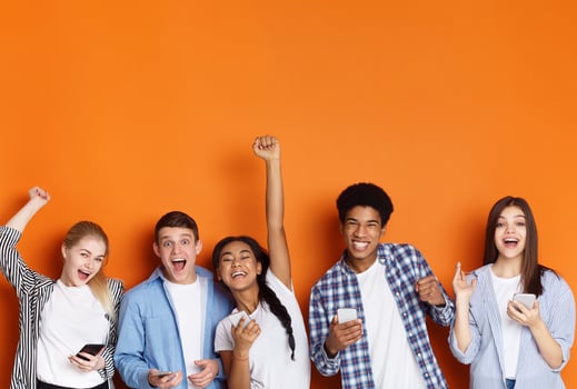 Excited friends with phones screaming and celebrating success over orange background, copy space photo